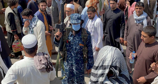 A member of Taliban security forces stands guard among crowds of people walking past in a street in Kabul, Afghanistan September 4, 2021. REUTERS/Stringer/File Photo