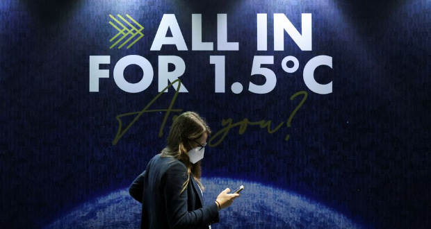 A delegate walks past a sign during the UN Climate Change Conference (COP26) in Glasgow, Scotland, Britain, November 11, 2021. REUTERS/Yves Herman