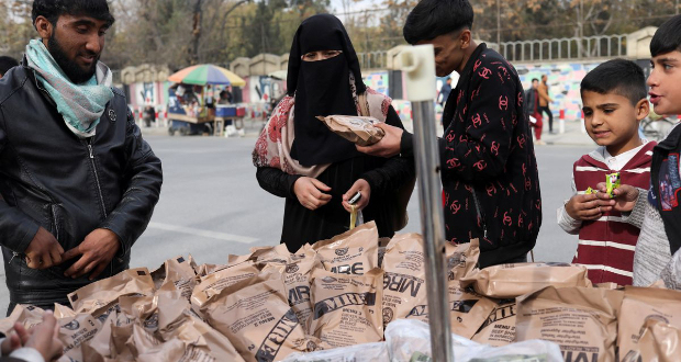 An Afghan woman buys food left behind by the US military from a peddler in Kabul, Afghanistan November 17, 2021. REUTERS/Ali Khara/File Photo