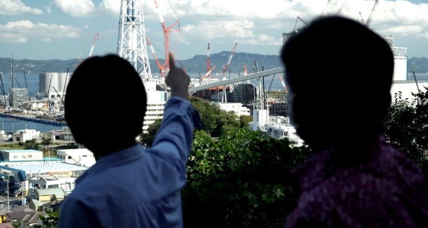 Activists looking out over Tokyo Bay at a new coal-fired power station under construction