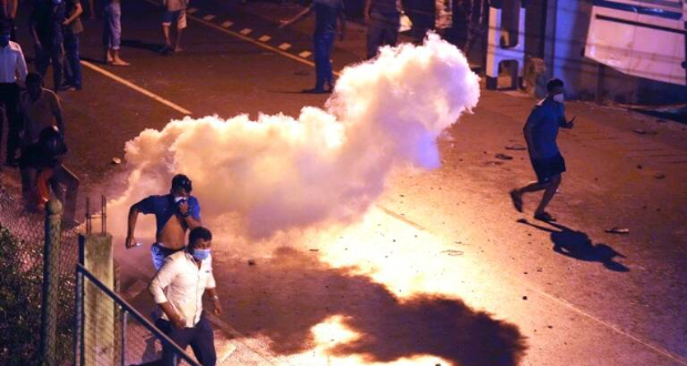 Protesters run to take cover as police uses tear gas shells to disperse them during a protest outside Sri Lankan president’s private residence on the outskirts of Colombo, Sri Lanka, Thursday, March 31, 2022. (AP Photo/Eranga Jayawardena)