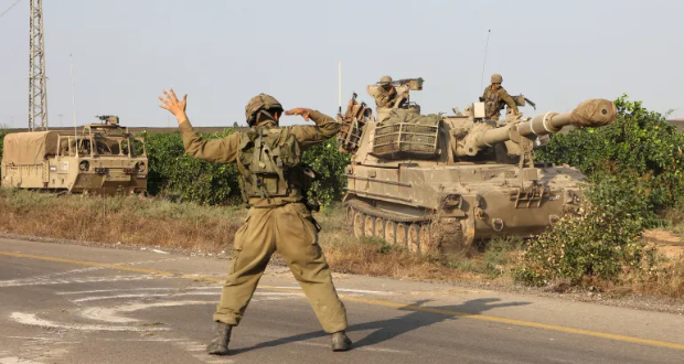 An Israeli soldier directs a military vehicle near the southern city of Ashkelon [Gil Cohen-Magen/AFP]