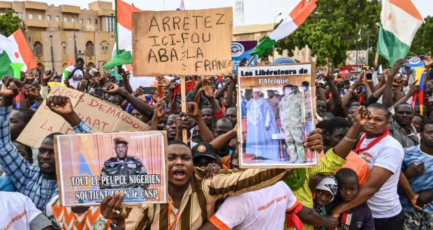 A supporter of Niger's National Concil for the Safeguard of the Homeland (CNSP) holds a placard of Niger's new military ruler, General Abdourahamane Tchiani, as they gather at Place de la Concertation in Niamey on August 20, 2023 [AFP]
