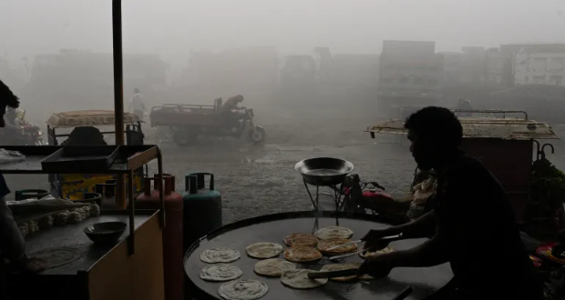 A labourer makes bread along a road amid heavy smog in Lahore [File: Arif Ali/AFP]