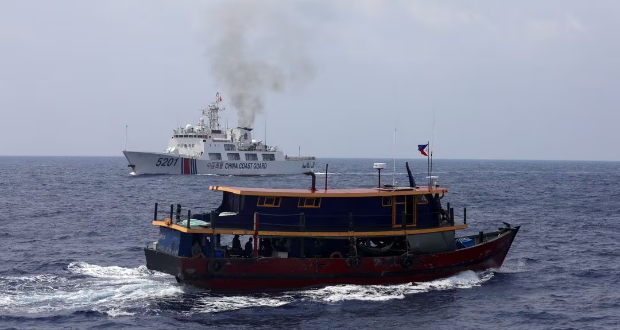 A Philippine supply boat sails near a Chinese Coast Guard ship during a resupply mission for Filipino troops stationed at a grounded warship in the South China Sea, October 4, 2023. REUTERS/Adrian Portugal/File Photo