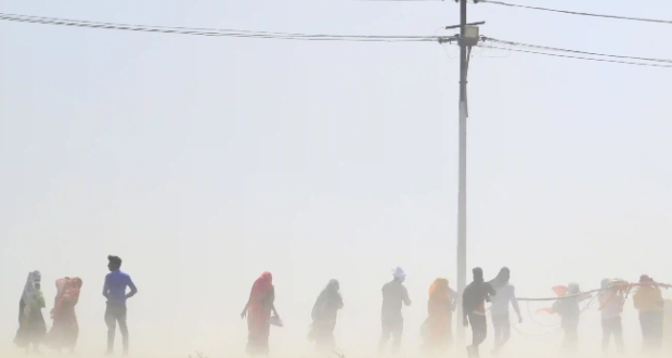 People walk through a dust storm in Prayagraj, India. Countries across the world are experiencing record temperatures. Photograph: Sanjay Kanojia/AFP/Getty Images