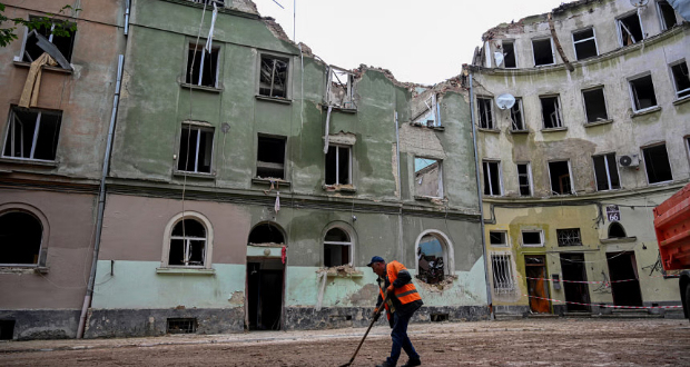 A communal worker sweeps outside an apartment building in the western Ukrainian city of Lviv, on July 7, 2023, a day after it was partially destroyed by a missile strike. The missile strike killed 10 people after the biggest Russian missile attack on civilian infrastructure in the western Ukrainian city since the invasion. Photo by YURIY DYACHYSHYN / AFP