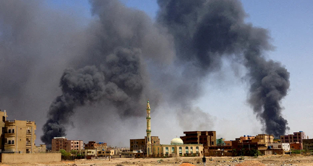 A man walks while smoke rises above buildings after aerial bombardments during clashes between the paramilitary Rapid Support Forces and the army in Khartoum North, Sudan, May 1, 2023