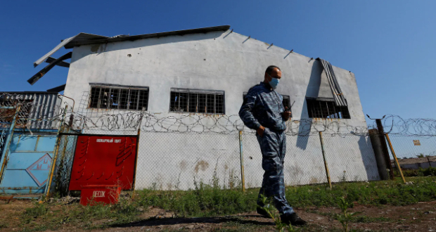 A security guard stands in front of the building in the settlement of Olenivka in the Donetsk Region, Ukraine August 10, 2022, in this picture taken during a media tour organised by the Russian Defence Ministry.