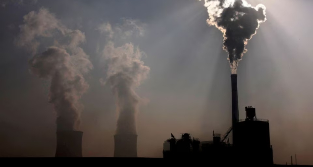 A coal-burning power plant can be seen behind a factory in the city of Baotou, in China's Inner Mongolia Autonomous Region, October 31, 2010. REUTERS/David Gray/File Photo