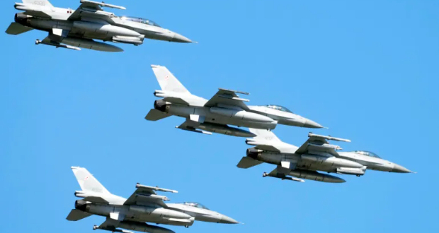 US-made F-16 fighter jets fly in the sky over Poland's capital, Warsaw, as they take part in a huge military parade on August 15, 2023 [Czarek Sokolowski/AP Photo]