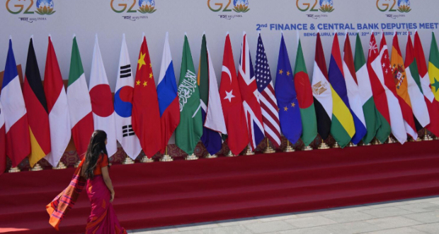 A delegate walks past a display of flags of participating countries at the venue of G-20 financial conclave on the outskirts of Bengaluru, India, Wednesday, Feb. 22, 2023. (AP Photo/Aijaz Rahi)