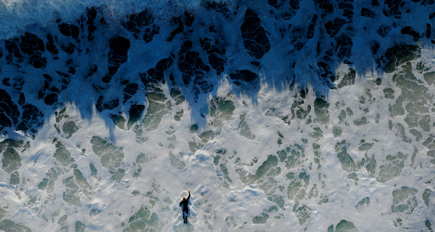 A surfer struggles to paddle against strong currents and through large breaking waves created by an approaching storm that will affect Southern California, January 4, 2024, in Huntington Beach. (Getty/Allen J. Schaben/Los Angeles Times)
