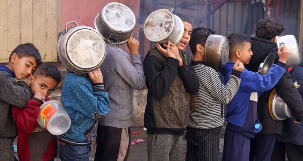 Palestinian children carry pots as they queue to receive food cooked by a charity kitchen, amid shortages in food supplies, as the conflict between Israel and Hamas continues, in Rafah in the southern Gaza Strip December 14, 2023. REUTERS/Saleh Salem/File Photo